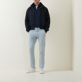 Model wearing Hugo Boss Orange Overdyed Slim-Leg Chinos in Open Grey, styled with a navy zip-up jacket and white trainers.