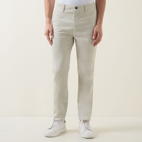 Model wearing Hugo Boss Orange Overdyed Tapered-Leg Chinos in Light Beige, styled with white trainers. Mid-rise, tapered fit, stretch satin fabric.