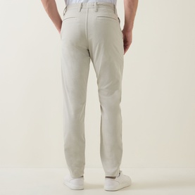 Model wearing Hugo Boss Orange Overdyed Tapered-Leg Chinos in light beige, rear view showing belt loops and rear jetted pockets, styled with white