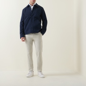 Model wearing Hugo Boss Orange Overdyed Tapered-Leg Chinos in Light Beige, styled with a navy overshirt and white trainers.