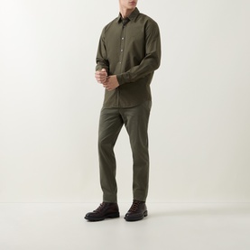 Model wearing Hugo Boss Orange Bright Green cotton chino trousers, styled with a matching olive shirt and dark lace-up boots.
