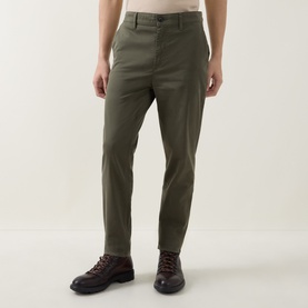 Model wearing Hugo Boss Orange chinos in Bright Green, slim fit with belt loops, styled with dark brown leather lace-up boots