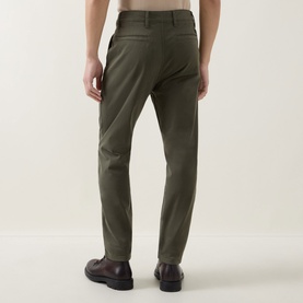 Model wearing Hugo Boss Orange Bright Green cotton chino trousers, slim tapered fit, shown from behind with dark leather shoes