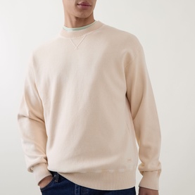 Model wearing Hugo Boss Orange Akapulko Logo Relaxed Fit Sweater in light pastel orange, crew neck with ribbed trims, styled with a light blue top