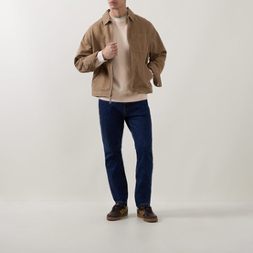 Model wearing Hugo Boss Orange Akapulko Light Orange cotton crew neck sweater, styled with beige jacket, dark navy jeans and brown shoes