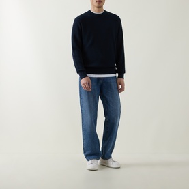 Model wearing Hugo Boss Orange Akipano Dark Blue crew neck knitted sweater, styled with mid-wash jeans and white trainers.