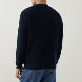 Model wearing Hugo Boss Orange Akipano Dark Blue knitted crew neck sweater, back view, styled with light blue jeans.