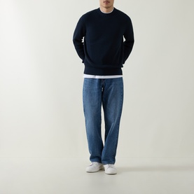 Model wearing Hugo Boss Orange Akipano Dark Blue crew neck knitted sweater, styled with light wash jeans and white trainers.