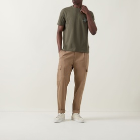 Model wearing Hugo Boss Orange Bright Green cotton crew neck T-shirt, styled with tan cargo trousers and white trainers.