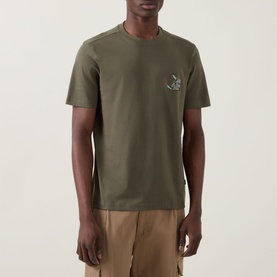 Model wearing Hugo Boss Orange Bright Green cotton crew neck T-shirt with small chest graphic embroidery, styled with khaki trousers.