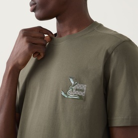 Model wearing Hugo Boss Orange Bright Green crew neck cotton T-shirt with small embroidered chest graphic detail.