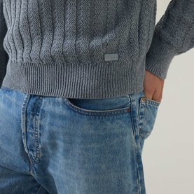 Model wearing Hugo Boss Orange Arkingo Texture Rib Sweater in Open Grey, styled with light blue wash denim jeans. Metal logo plaque visible near