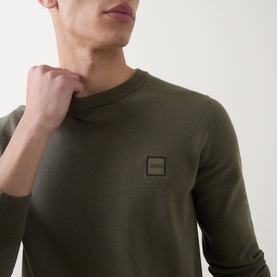Model wearing Hugo Boss Orange Kanovano Logo Sweater in Bright Green, crew neck with tonal logo patch, ribbed trims, close-up detail shot