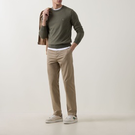 Model wearing Hugo Boss Orange Kanovano Logo Sweater in Bright Green, styled with white tee, beige chinos and white trainers, jacket over shoulder