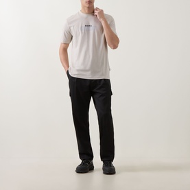 Model wearing Hugo Boss Orange light beige crew neck T-shirt in cotton, styled with black cargo trousers and black shoes.