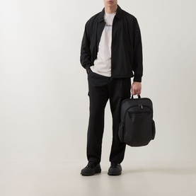 Model wearing Hugo Boss Orange Light Beige crew neck T-shirt, styled with black bomber jacket, black trousers and shoes, carrying black bag.