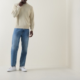 Model wearing Hugo Boss Orange Kosido Knitted Sweater in light beige crew neck, styled with mid-blue jeans and white trainers