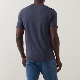 Model wearing Hugo Boss Orange Tales Logo T-Shirt in dark blue, back view, crew neck, short sleeves, styled with blue jeans.