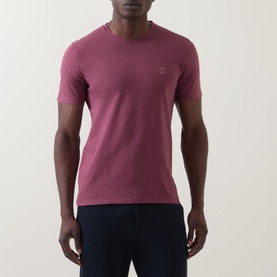 Model wearing Hugo Boss Orange Tales Logo T-Shirt in medium red, crew neck with logo patch, paired with navy trousers.