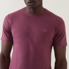 Model wearing Hugo Boss Orange Tales Logo T-Shirt in medium red, featuring a crew neck and small logo patch at chest.