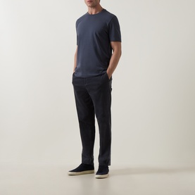Model wearing Hugo Boss Orange T Chup Logo T-Shirt in dark blue, crew neck, styled with navy trousers and beige slip-on shoes.