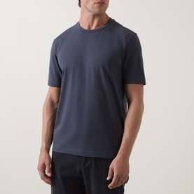 Model wearing Hugo Boss Orange T Chup Logo T-Shirt in dark blue, crew neck, short sleeves, with dark trousers visible below.