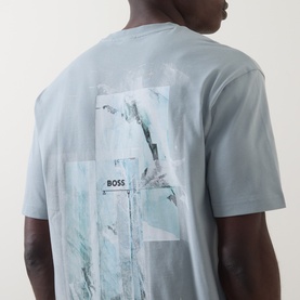 Model wearing Hugo Boss Orange Te Frame Logo Back Graphic T-Shirt in Open Grey, showing rear mountain-print graphic with logo patch detail.