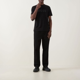 Model wearing Hugo Boss Orange Te Logo T-Shirt in black with tonal logo print, styled with black trousers and black shoes.
