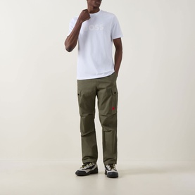 Model wearing Hugo Boss Orange Te Logo T-Shirt in white with crew neck, paired with olive cargo trousers and trail trainers.