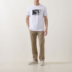 Model wearing Hugo Boss Orange Te Motors Logo Graphic T-Shirt in white with black photo print, styled with tan chinos and white trainers.
