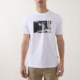 Model wearing Hugo Boss Orange Te Motors Logo Graphic T-Shirt in white with black car graphic print, styled with khaki trousers.