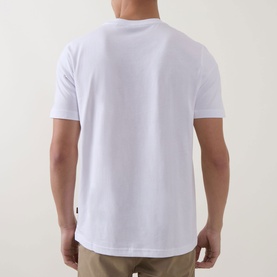 Model wearing Hugo Boss Orange Te Motors Logo Graphic T-Shirt in white, back view, crew neck, short sleeves, paired with beige trousers.