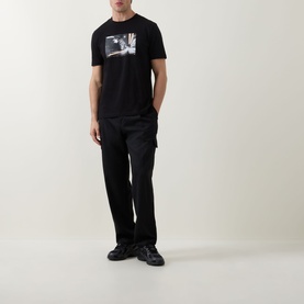 Model wearing Hugo Boss Orange black crew neck T-shirt with graphic print, styled with black cargo trousers and chunky trainers.