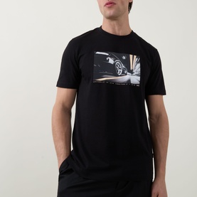 Model wearing Hugo Boss Orange black crew neck T-shirt with photographic car graphic print on chest, styled with black trousers.