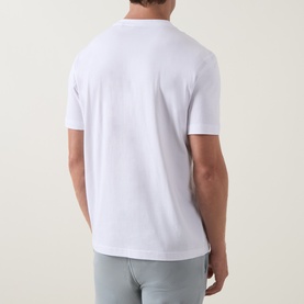 Model wearing Hugo Boss Orange Te Motors Logo Graphic T-Shirt in white, rear view, crew neck, short sleeves, paired with light grey trousers.