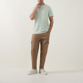 Model wearing Hugo Boss Orange Open Green cotton crew neck T-shirt, styled with tan cargo trousers and white trainers.