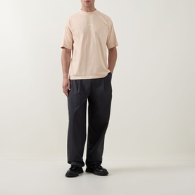Model wearing Hugo Boss Orange light pastel orange cotton crew neck T-shirt with dark charcoal trousers and black loafers.
