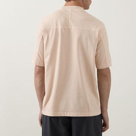 Model wearing Hugo Boss Orange light pastel orange cotton crew neck T-shirt, back view, paired with dark trousers.