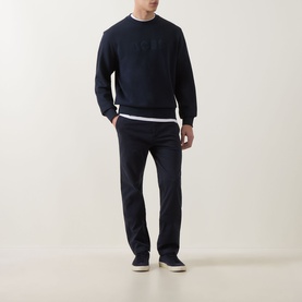 Model wearing Hugo Boss Orange dark blue cotton crew neck sweatshirt with tonal logo, styled with navy trousers and white T-shirt.