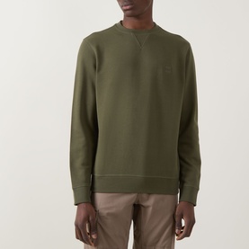 Model wearing Hugo Boss Orange Westart Logo Sweater in Bright Green, crew neck with tonal chest logo, paired with beige trousers