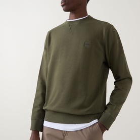 Model wearing Hugo Boss Orange Westart Logo Sweater in Bright Green, crew neck with tonal chest badge, styled over white layered tee