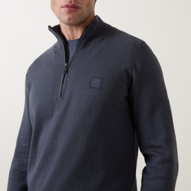 Model wearing Hugo Boss Orange Kanobix Half-Zip Sweater in Dark Blue, showing logo badge detail and funnel neckline close-up