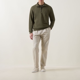 Model wearing Hugo Boss Orange Bright Green cotton half-zip sweatshirt with cream trousers and white trainers