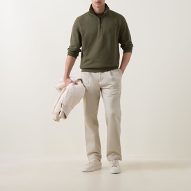 Model wearing Hugo Boss Orange Bright Green cotton half-zip sweatshirt, styled with stone chinos and white trainers, carrying a light jacket.