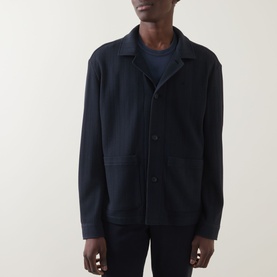 Model wearing Hugo Boss Carper Stripe Overshirt in dark blue, flat collar, button fastening, patch pockets, styled over navy crew-neck tee