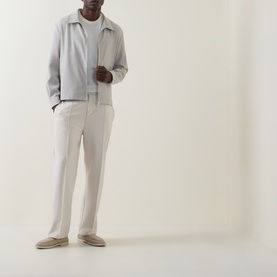 Model wearing Hugo Boss light beige virgin wool jacket with zip front, styled with cream trousers and beige loafers.