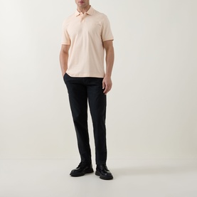 Model wearing Hugo Boss Orange light pastel orange cotton polo shirt, styled with black slim trousers and black leather shoes.
