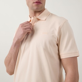 Model wearing Hugo Boss Orange polo shirt in light pastel orange, short sleeves, ribbed collar, with small logo embroidery at chest