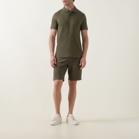 Model wearing Hugo Boss Orange bright green cotton polo shirt, styled with matching shorts and white trainers