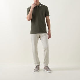 Model wearing Hugo Boss Orange Passerford Tipped Logo Polo Shirt in Bright Green with tipped collar, styled with ecru trousers and grey trainers.